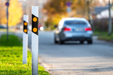 poles at the traffic safety speed bumps in a residential area, defocused background with a car