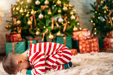 portrait of a little boy at Christmas with a sad face on the background of a Christmas tree