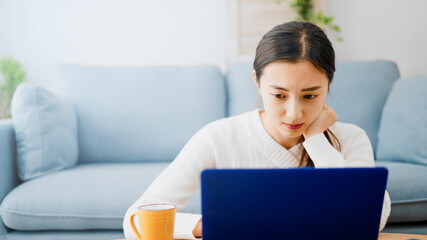 ソファーでノートパソコンを使う若い女性