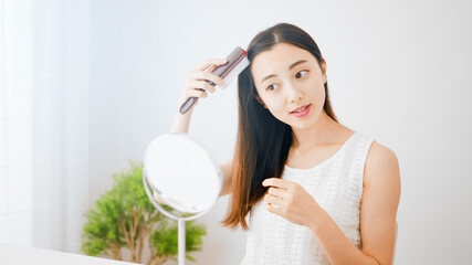 Naklejka premium 髪にブラシをかける若い女性