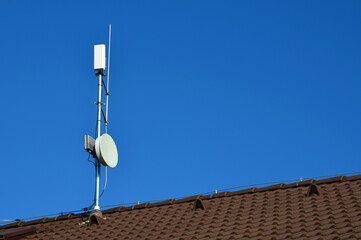 an internet signal amplifier is located on roof of the family house. parabolic antennas and...