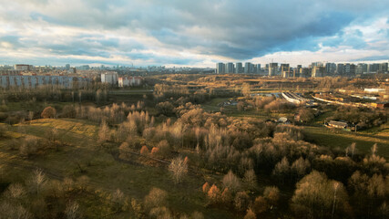Flight over city blocks. There is a park area nearby. Flying in the backlight of the setting sun. Aerial photography.