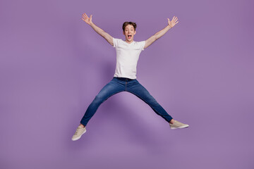 Fototapeta na wymiar Full length photo of young man good mood jump energetic active cool isolated on violet color background