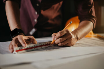 Concept architects or engineer holding pen pointing equipment architects on the desk with a blueprint in the office.