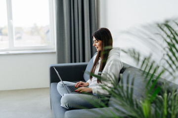 Young woman using a laptop while relaxing on the couch