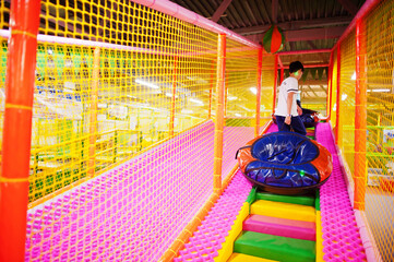 Fototapeta premium Happy two brothers in tubing donuts enjoying slides in fun children center.