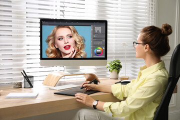 Professional retoucher working on graphic tablet at desk in office