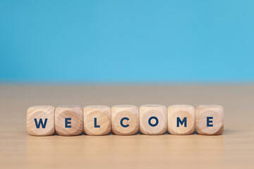Wooden cube with the word WELCOME on the wooden floor.