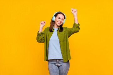 Photo of pretty charming young woman dressed green shirt headphones dancing smiling isolated yellow color background