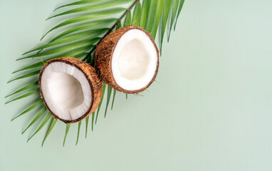 Fototapeta na wymiar Summer banner and poster. Two halves of coconut and tropical leaf on green background.