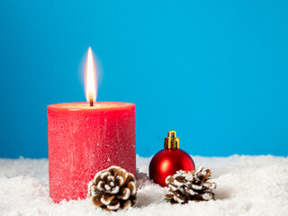Red Christmas candle and Christmas decorations on a blue background.