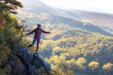 a girl stands on the edge of a cliff and looks into the distance. travel and sports.