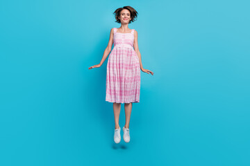 Full length photo of sportive young lady jump wear pink long sarafan footwear isolated on blue background