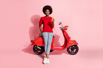 Obraz na płótnie Canvas Full body photo brunette afro american girl wear casual outfit hold phone sit motorbike excited isolated on pink color background