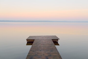 Forest lake (river) at sunrise. Wooden pier (boardwalk). Soft sunlight, mist, reflections on water....