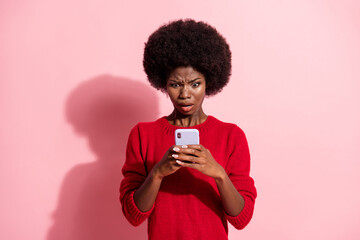 Portrait of attractive nervous outraged girl using device bad news media dislike isolated over pink...