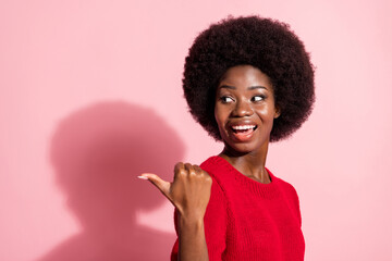 Photo of attractive impressed dark skin girl look indicate thumb empty space isolated on pink color background