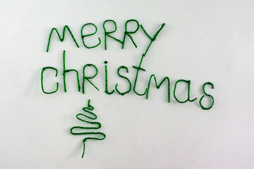 Inscription Merry CHRISTMAS is made of green tinsel on a white background. Isolated.