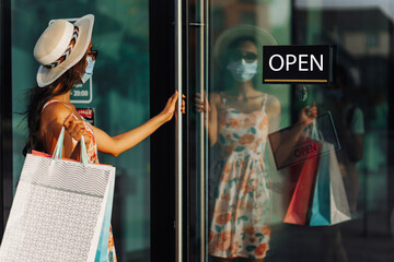 woman wearing a medical mask, with shopping bags enjoying shopping on Black Friday, woman entering a store with an open