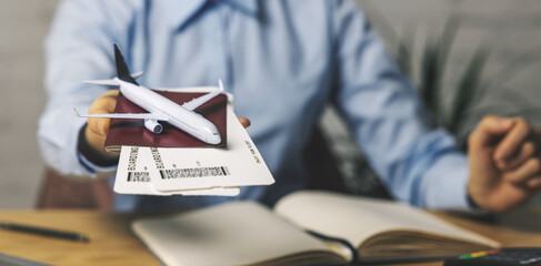 travel agent with flight tickets and plane model in hand at agency office. tourism service. copy space - obrazy, fototapety, plakaty