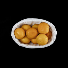 Small oval basket with beautiful tangerines on a black isolated background