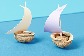 Sailboats made of nutshell and paper on blue background. DIY ship toys.