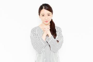 お願いのポーズをするカジュアルな服装の女性