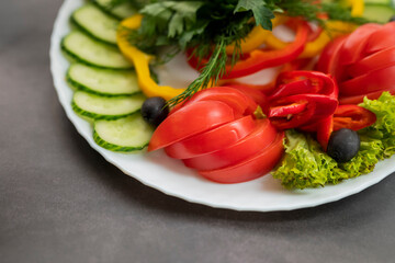 Assorted fresh vegetables on a plate .Dish of cucumbers, paprika, tomato and basil with parsley and cucumber