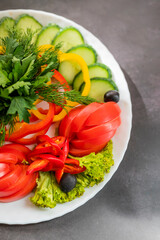 Assorted fresh vegetables on a plate .Dish of cucumbers, paprika, tomato and basil with parsley and cucumber