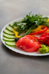 Assorted fresh vegetables on a plate .Dish of cucumbers, paprika, tomato and basil with parsley and cucumber