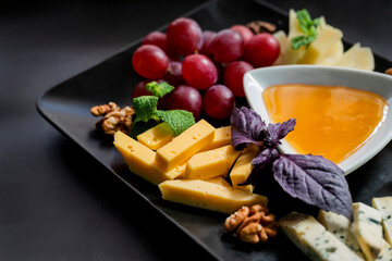 assorted food parmesan cheese with grapes and blue cheese and honey on a plate in a restaurant
