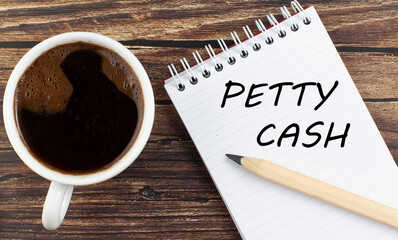 PETTY CASH text on notebook with coffee on wooden background