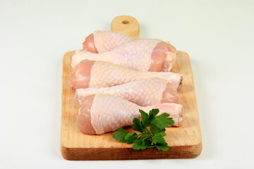 Fresh chicken drumsticks on wooden board isolated on white. Group of Raw Chicken legs isolated on white background 