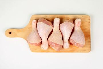 Fresh chicken drumsticks on wooden board isolated on white. Group of Raw Chicken legs isolated on...