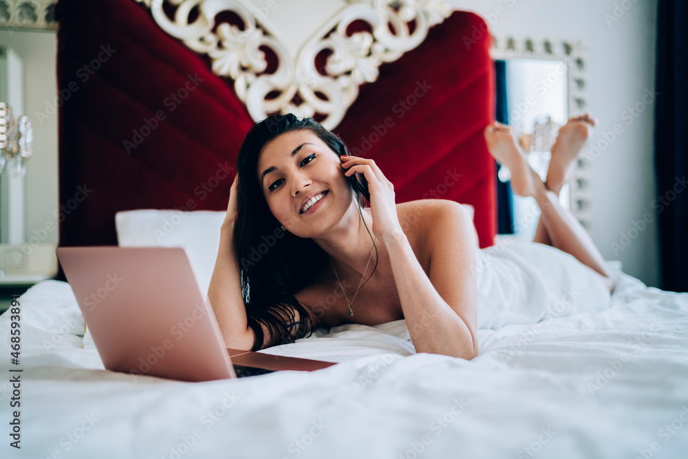 Poster portrait of influence blogger with digital netbook computer lying at comfortable bed in hotel room a