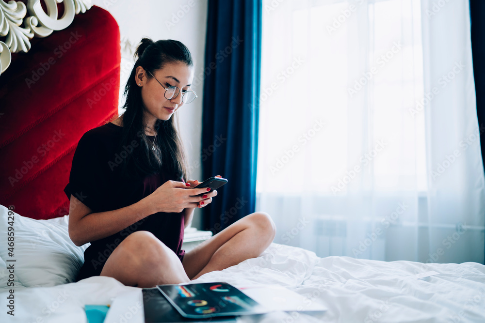 Poster millennial female blogger browsing web page on modern cellular device using hotel wifi connection in