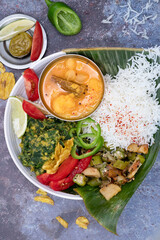 Indian vegan bowl with sambar, spinach and lentils, vegetables and rice on banana leaf
