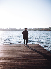 a young guy with a beard looks melancholically at the view of the lake