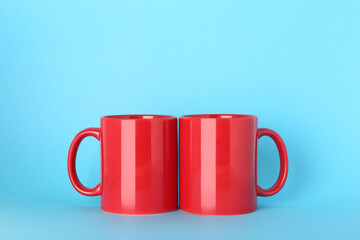 Blank red ceramic mugs on light blue background