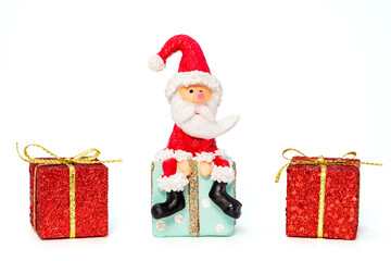 Weihnachtsmann sitzend, mit drei Weihnachtspackerl vor einem weißen Hintergrund