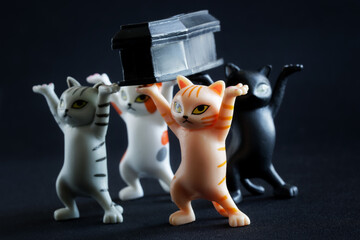 Toy kittens carry a black coffin. Concept of the custom of dancing with a coffin in Ghana. Black...