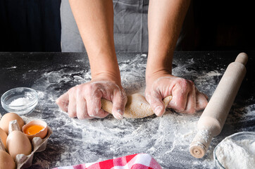 Chef hands cooking dough on dark wooden background. Food concept.