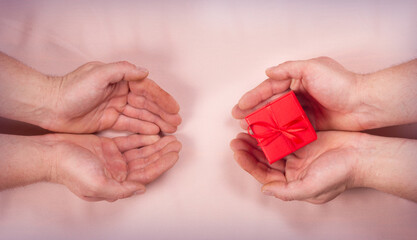 Gay homosexual couple hands gives red box gift with ribbon on brown background valentines day concept