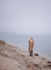 Fototapeta na wymiar a girl on an autumn beach walks with a Pekingese dog, a foggy morning