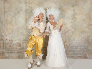 Fototapeta na wymiar Fun couple in Baroque style clothes and white wigs in studio