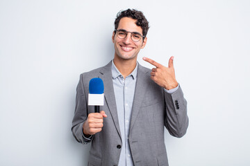 young handsome man smiling confidently pointing to own broad smile. presenter with microphone