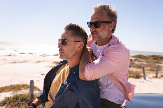Happy caucasian gay male couple embracing and enjoying the view at the seaside - Powered by Adobe