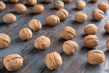 Beautiful ripe walnuts in shells on a textured vintage wooden background.