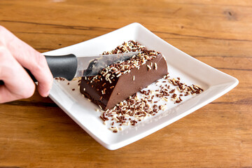Chocolate pudding with sprinkles, knife cutting piece with delicious chocolate dessert