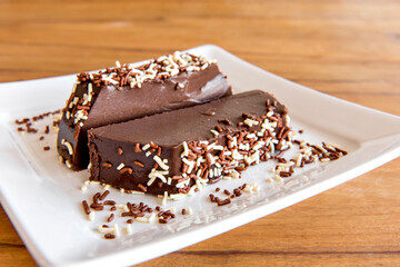Chocolate pudding with sprinkles, piece of delicious chocolate dessert on wooden table.